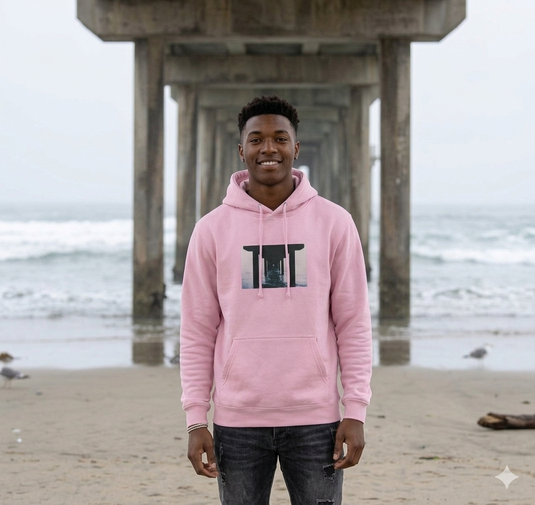 Person wearing a pink WATY hoodie with a pier graphic at the beach